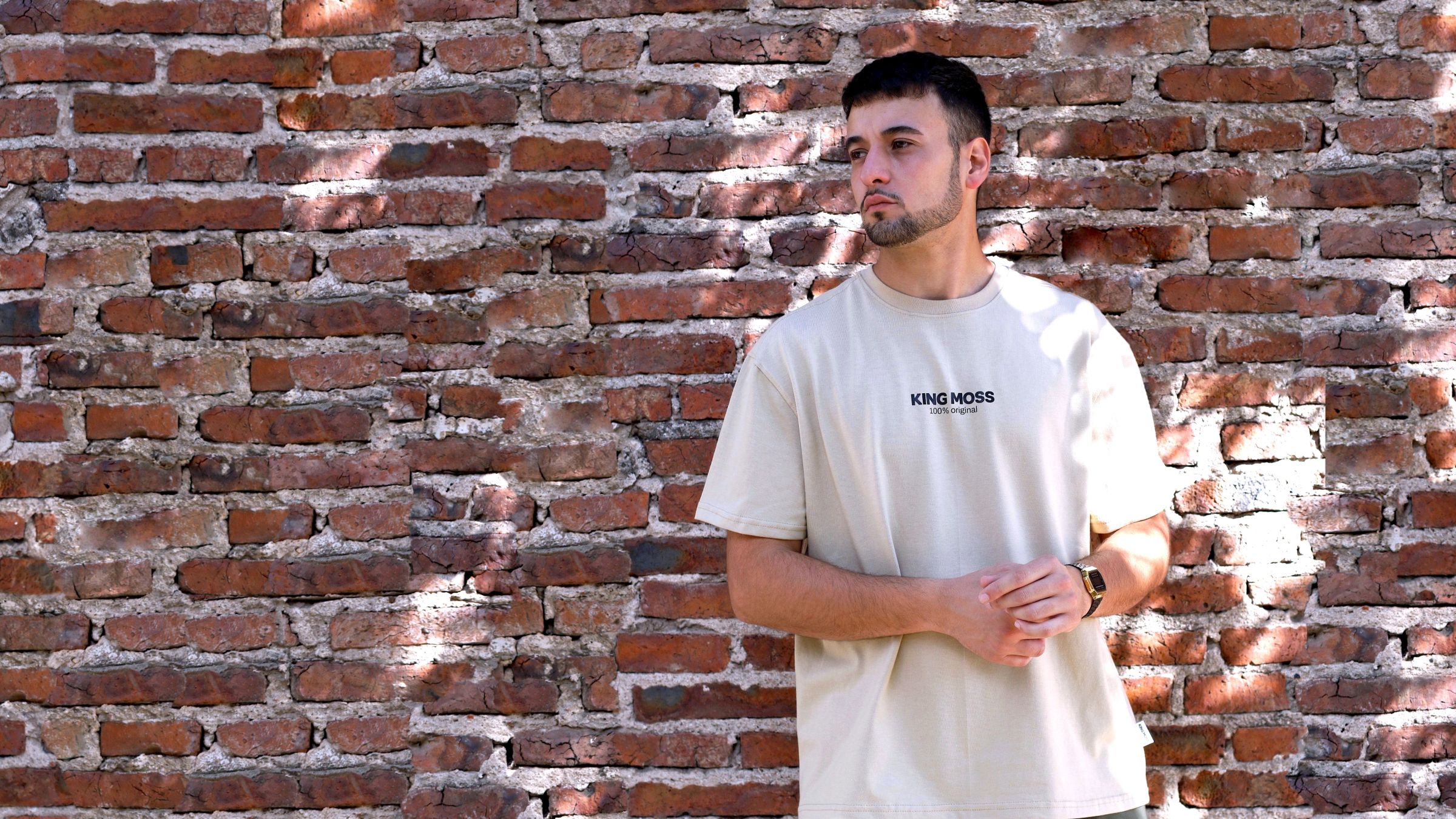 Modelo con la remera King Moss contra un paredón de ladrillo